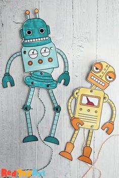 paper cut out of two robots on a white wooden background with twine cord and string