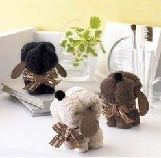 three small stuffed animals sitting on top of a white table next to a plant and toothbrush