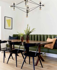 a dining room table with four chairs and a bench in front of it, next to a green couch