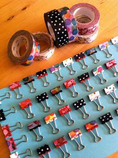 several rolls of washi tape are arranged on a peg board with clothes pins attached to them