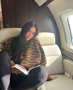 a woman sitting in an airplane reading a book