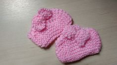 two pink knitted mittens sitting on top of a wooden table