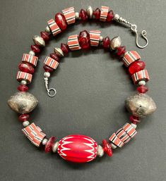 6 layers vintage red rare chevron Rosetta star glass bead surrounded by vintage millefiori Venetian red stripped beads and red Vaseline trade beads.  In The Center a huge 6 layers chevron glass Handmade, red and white bead that measures 38mm x 30mm.  It is Surrounded by Multiple different sizes, shapes and designs of mixed striped vintage Venetian millefiori beads that measure approximately 15mm and red Vaseline glass beads ranging from 12mm to 16mm.   There are 2 vintage Bicone silver Berber be Luxury Bohemian Red Beads And Cabochons, Artisan Red Spacer Beads, Festive Red Artisan Jewelry, Festive Artisan Red Jewelry, Unique Red Beaded Necklaces For Festive Occasions, Red Artisan Necklace With Round Beads, Artisan Red Jewelry For Collectors, Vintage Red Necklace With Large Beads, Artisan Red Necklace With Round Beads