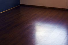 an empty room with hard wood flooring and blue walls, sunlight shining through the window