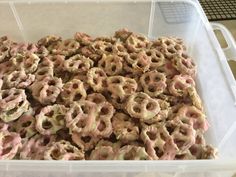 a plastic container filled with lots of pink and white donuts on top of a table