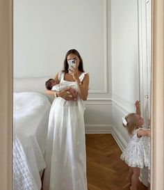 a woman taking a selfie in front of a mirror with her baby and toddler