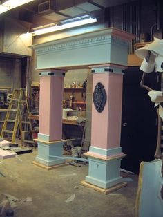 a pink and white clock tower sitting inside of a building next to other items on the floor