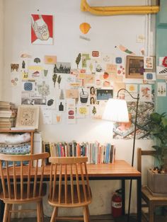 two wooden chairs sitting in front of a desk with books on it and pictures hanging on the wall