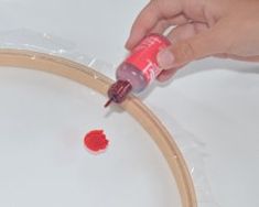 a person is painting a wooden hoop with red paint