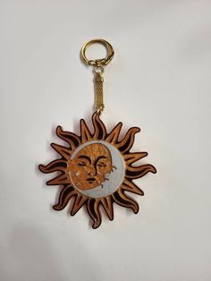 a wooden keychain with an image of a sun and moon on the front