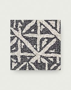 an abstract black and white pattern on a square tile wall hanging in a room with gray walls