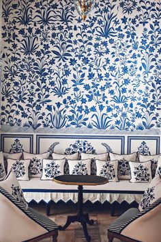 a living room with blue and white wallpaper, two chairs and a table in front of it