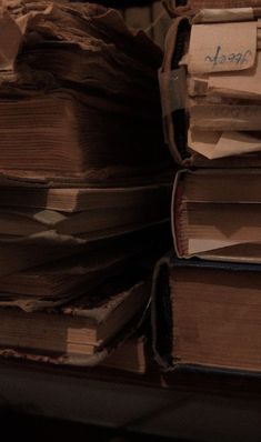 a stack of old books sitting on top of a wooden table next to a pile of papers