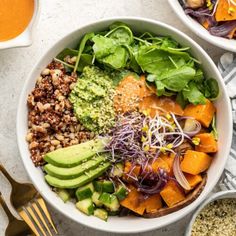 two bowls filled with different types of vegetables and sauces on top of a table