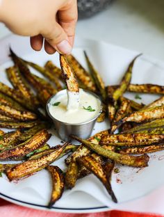 a person dipping some kind of sauce on top of fried asparagus with ranch dressing