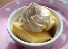 a small bowl filled with whipped cream on top of a pink and white polka dot plate