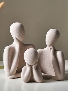 two white ceramic figurines sitting next to each other on top of a table