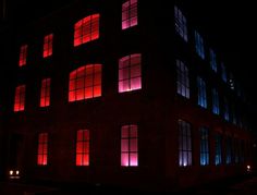 the building is lit up with red and blue lights in it's windows at night