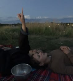 a man laying on top of a blanket next to a metal bowl