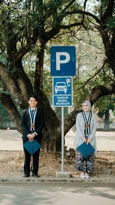 two people standing in front of a parking sign