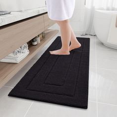 a person standing on a black rug in a bathroom