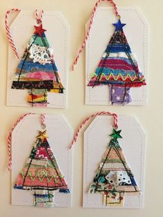 four small christmas trees are hanging from twine tags on the wall, each decorated with different patterns and colors