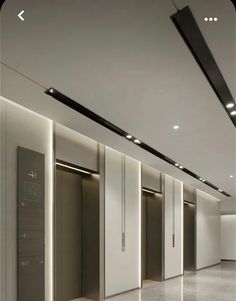 an empty room with several doors and lights on the ceiling is lit by recessed lighting