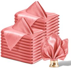 a stack of pink napkins with satin bows on each one and a gold bell in the middle