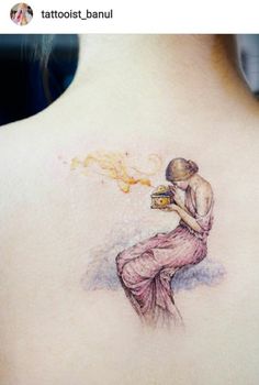 a woman with a tattoo on her back is holding a book and looking at the sky