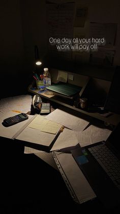 a desk with a laptop, calculator and notebook on it in the dark