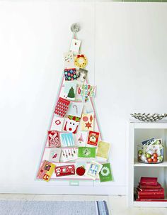 a christmas tree made out of cards and magnets on the wall next to a book shelf