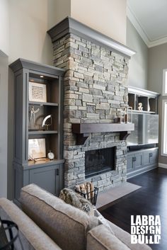 a living room with a stone fireplace and built - in entertainment center next to a large window