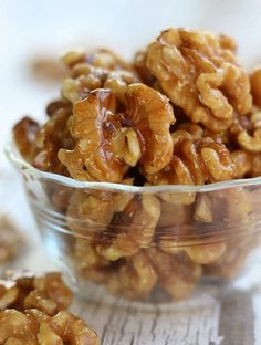 a glass bowl filled with walnuts on top of a wooden table