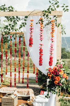 an outdoor ceremony with flowers and greenery hanging from the ceiling, along with other decorations