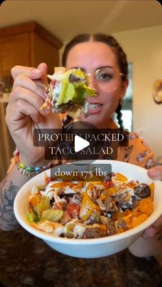 a woman holding up a bowl of food with the caption, protein packed taco salad down 75lbs