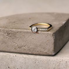 a gold and diamond ring sitting on top of a cement block