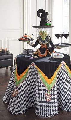 the table is decorated with black and white checkered cloths, an elaborate witch hat, and two wine glasses