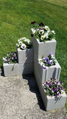 four cement blocks with flowers growing out of them