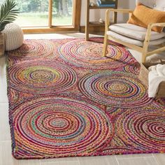 a colorful area rug in a living room with a chair and large window behind it