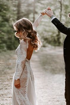 the bride and groom are dancing together in the woods at their outdoor wedding ceremony, dressed in black tuxedo with white lace