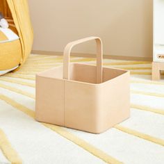 a beige basket sitting on top of a white rug