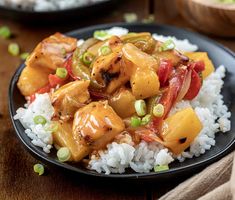 a black plate topped with rice and chicken