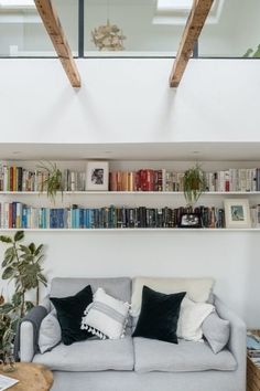 a living room filled with lots of furniture and bookshelves on top of it