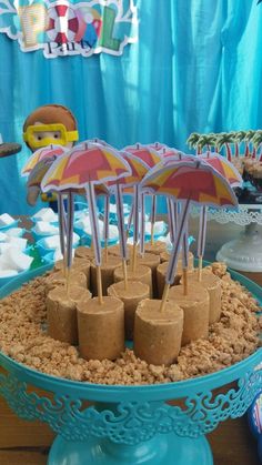 there are many desserts on the table with umbrellas in them and sand under them