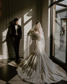 a bride and groom standing next to each other in front of an open window at their wedding