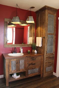 a bathroom with red walls and wooden cabinetry, two lights hanging over the sink