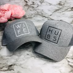 two hats sitting on top of a marble counter next to pink flowers and peonies