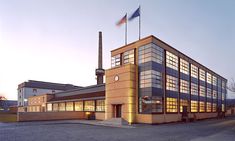 an industrial building lit up at night with the sun shining on it's windows