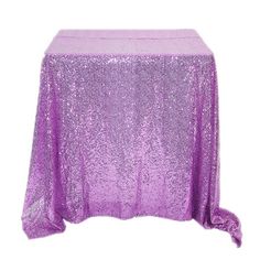 a purple sequin table cloth on top of a white table with an orange flame in the background