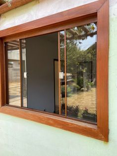 an open window on the side of a house with wood trim and glass panes